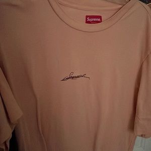 It is a salmon cursive embroidered supreme shirt from WK 18